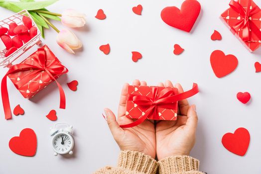 Valentine's day and birthday. Woman hands holding gift or present box decorated and red heart surprise on white background, Female's hand hold gift box package in craft paper Top view flat lay