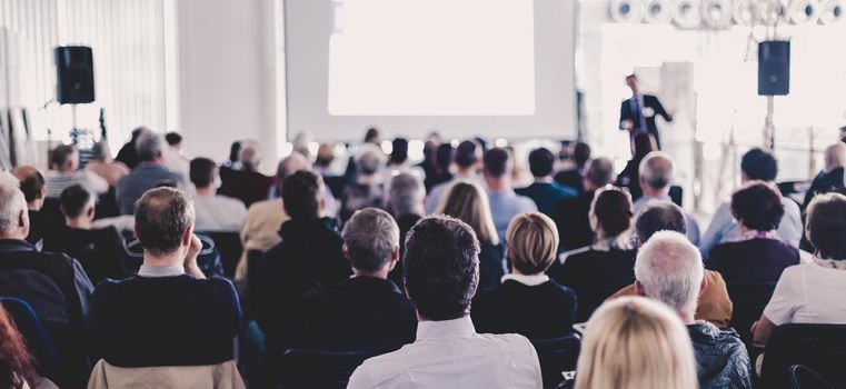 Speaker Giving a Talk at Business Meeting. Audience in the conference hall. Business and Entrepreneurship. Panoramic composition suitable for banners.