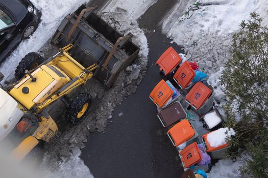 Madrid, Spain - January 17, 2021: An excavator machine, snow plow, clears and tears the ice from the streets of the Retiro district, on a snowy day, due to the Filomena polar cold front.