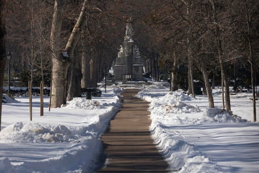 Madrid, Spain - January 17, 2021: Road without snow inside the Buen Retiro public park, with a lot of accumulated snow, without removing it for days, after the polar storm Filomena.