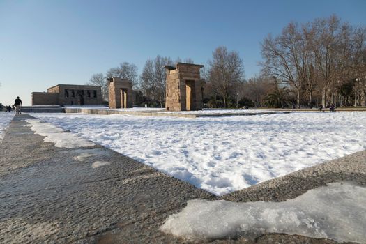 Madrid, Spain - January 17, 2021: The famous reconstructed Egyptian temple of Debod, surrounded by unremoved snow, on a sunny day, after the polar storm Filomena.