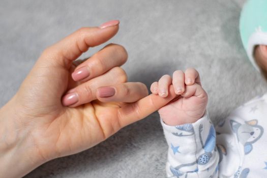 Small newborn child holds his mother finger.