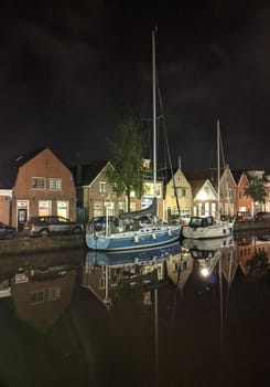 Sailboats along the canal at night in Sneek, Friesland, The Netherlands