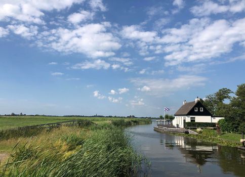 House with a frisian flag next to a lake around Oudega in Friesland, The Netherlands