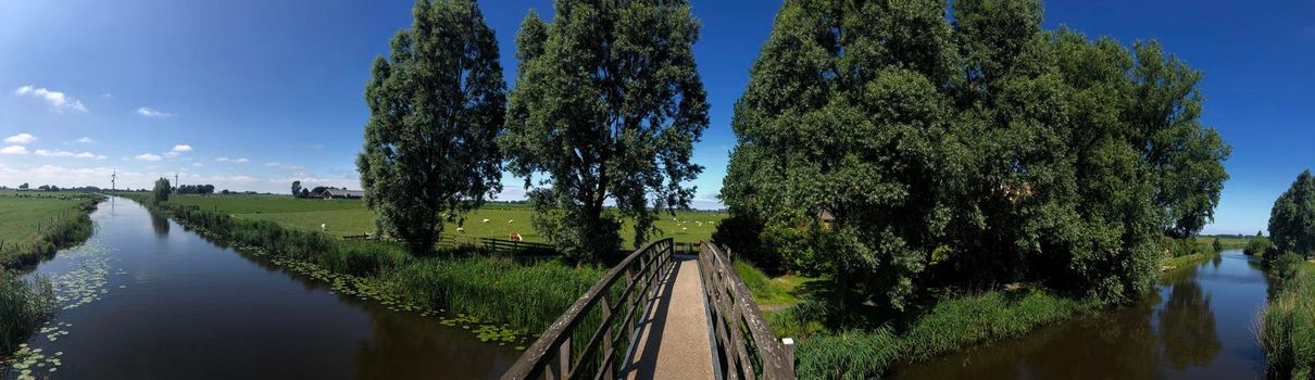 Panorama from a bridge over a canal in between Bartlehiem and Aldtsjerk in Friesland, The Netherlands