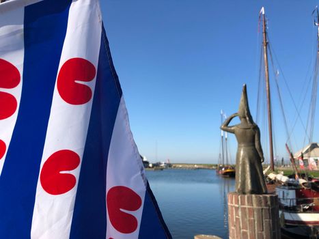 Frisian flag and Lady of Stavoren statue in the harbor of Stavoren, Friesland The Netherlands