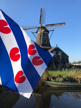 Frisian flag in front of the windmill in IJlst during autumn in Friesland, The Netherlands