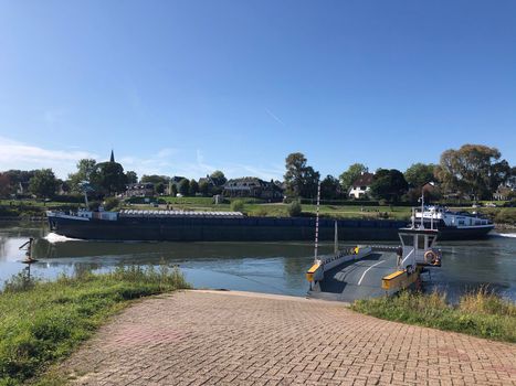 Ferry and cargo ship at the IJssel river between Olburgen and Dieren, Gelderland The Netherlands