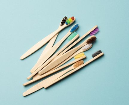 multicolored wooden toothbrushes on a blue background, plastic rejection concept, zero waste, top view