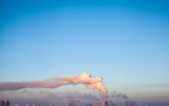 White thick smoke from the boiler room chimney. Smoke against the blue sky. Air pollution. Heating of the city. Industrial zone.