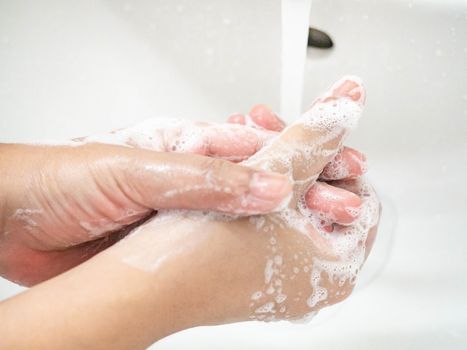 A woman cleaning hands Use hand soap until white bubbles form in the basin.