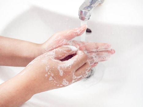 A woman cleaning hands Use hand soap until white bubbles form in the basin.
