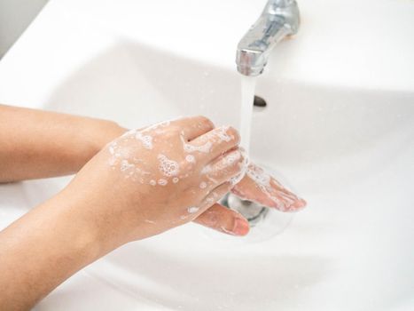 A woman cleaning hands Use hand soap until white bubbles form in the basin.