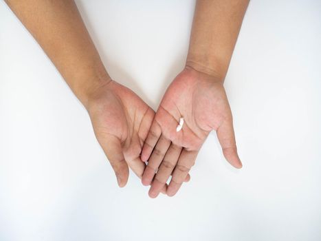 A woman's hand squeezes cream onto her hand to apply moisturizer to her hand.