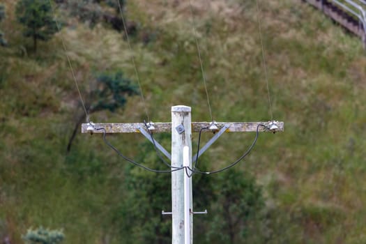 A wooden telephone pole with wires and terminal connectors in front of a bright blue sky background