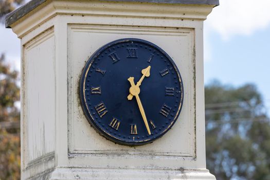 An old blue outdoor clock face with golden hands on a white background