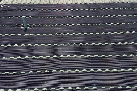 Hot water pipes on a green tiled roof in the bright sunshine.