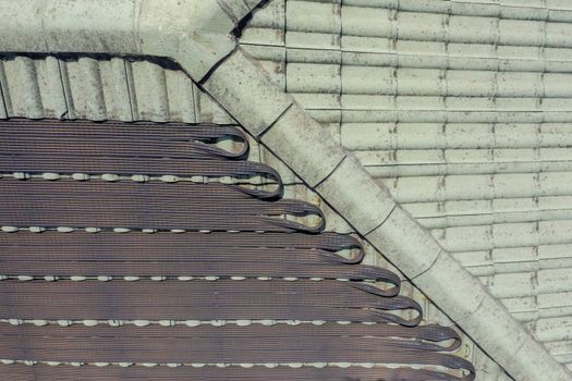 Hot water pipes on a green tiled roof in the bright sunshine.