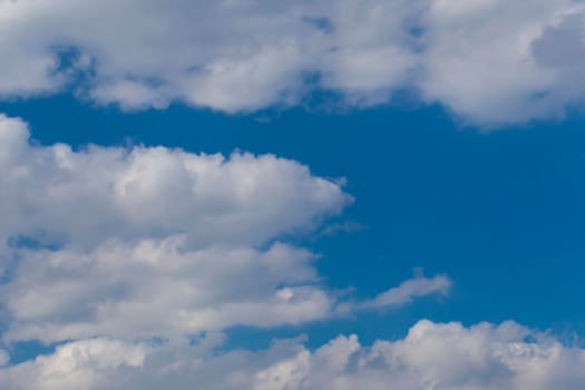 Slightly grey Cumulus clouds in a bright blue sky