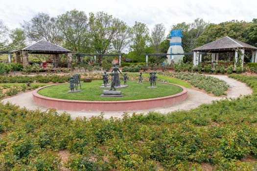 Statues and buildings in a large garden with flowers and plants