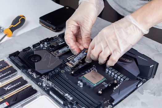 Moscow, Russia - 25 Dec 2020: Technician installing new hard disk drive m2 to desktop computer. Electronic repair shop, technology renovation, business, concept repairs.