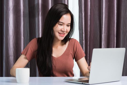Work from home, Smiling Happy Asian business young beautiful woman sitting on desk workspace video call conferencing with team by webcam laptop computer technology at home office