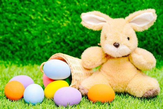 Easter bunny toy and Easter eggs in basket on green grass