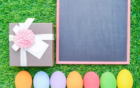 Close up Colorful easter eggs on green grass and blackboard mockup with copy space