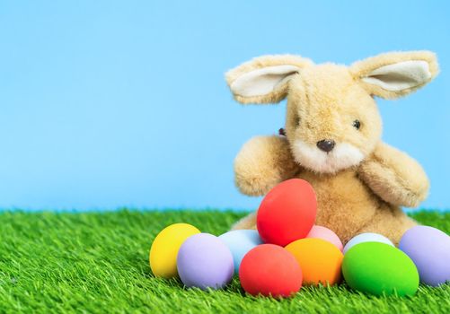 Colorful easter eggs and bunny on grass with blue background