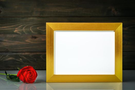 Picture mock up with golden frame and red roses flowers on table with copy space