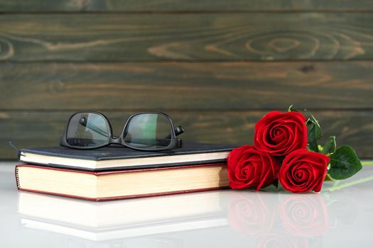 Red roses on table and book with copy space, Valentine's day background with red roses