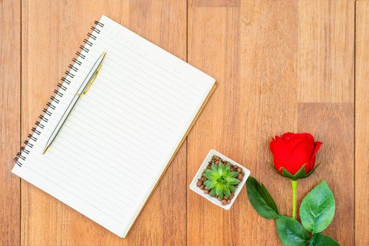 Top view Red roses on wooden table and pen on notepad on wood deck ,Valentines day concept