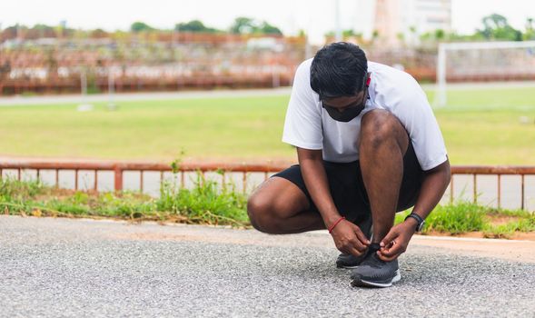 Close up Asian sport runner black man wear watch sitting he trying shoelace running shoes getting ready for jogging and run at the outdoor street health park, healthy exercise workout concept