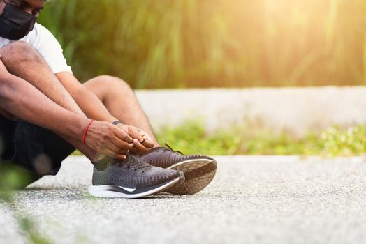 Close up Asian sport runner black man wear watch sitting he trying shoelace running shoes getting ready for jogging and run outdoor street health park with copy space, healthy exercise workout concept