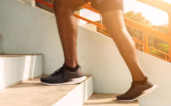 Close up athlete shoes of legs young sport runner black man step running up to climbing stairs doing training cardio sport workout at the outdoor street, healthy exercise before workout concept