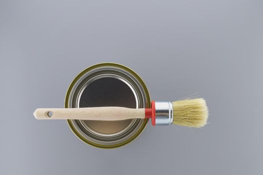 Clean bristle brush on tin of paint over a grey background. New color, decorating or renovations concept