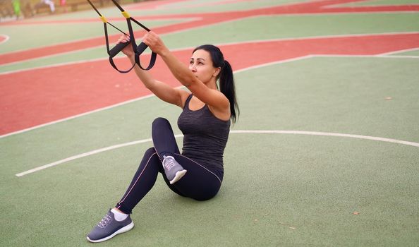 Girl athlete training sportground Mixed race young adult woman workout suspension system Healthy lifestyle Stretching outdoors playground. Make your body machine