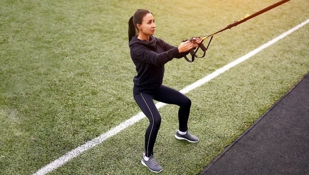 Girl athlete training sportground Mixed race young adult woman workout suspension system Healthy lifestyle Stretching outdoors playground. Make your body machine