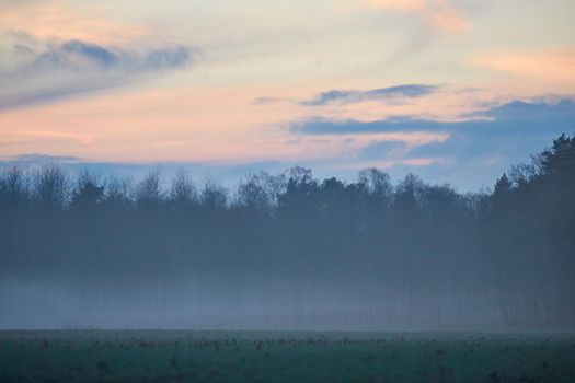 A landscape in the evening with fog and sunset