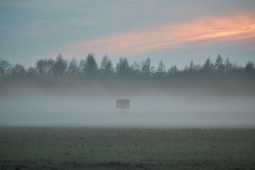A landscape in the evening with fog and sunset