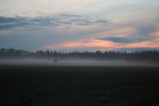 A landscape in the evening with fog and sunset