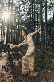 A romantic woman in a dress in a coniferous forest is dancing on the ground and fallen cones. High quality photo