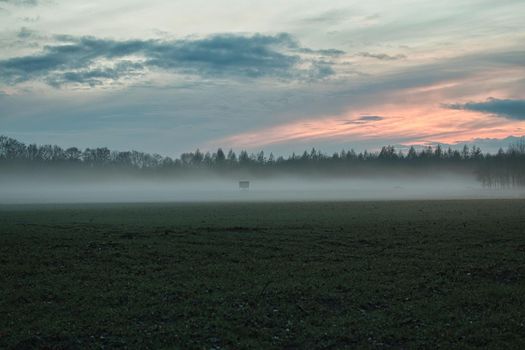 A landscape in the evening with fog and sunset