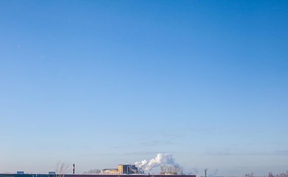 White thick smoke from the boiler room chimney. Smoke against the blue sky. Air pollution. Heating of the city. Industrial zone.