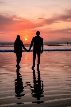 couple of men and women mid-age watching the sunset on the beach of Tofino Vancouver Island Canada, beautiful sunset on the beach with pink-purple colors in the sky. Canada Tofino