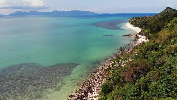 Green jungle and stony beach near sea. Tropical rainforest and rocks near calm blue sea on white sandy shore of Koh Samui paradise island, Thailand. Dream beach drone view. Relax and holiday concept