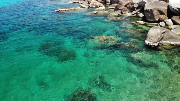 Calm sea water near stones. Peaceful blue sea water and gray boulders in perfect place for snorkeling on Koh Tao Island on sunny day in Thailand. Natural background texture