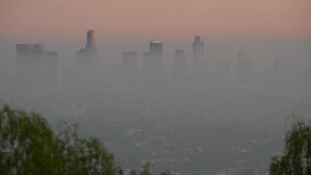 Highrise skyscrapers of metropolis in smog, Los Angeles, California USA. Air toxic pollution and misty urban downtown skyline. Cityscape in dirty fog. Low visibility in city with ecology problems.