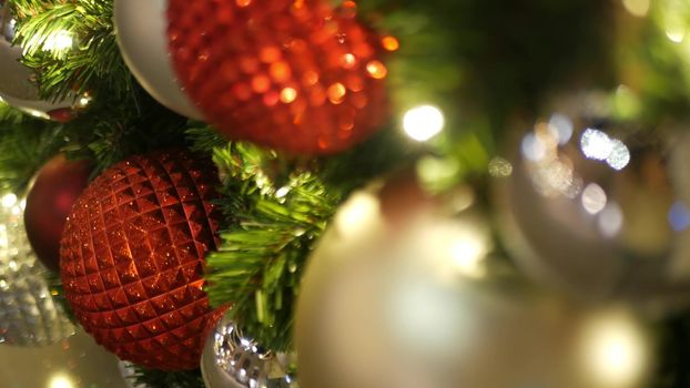 Closeup of Festively Decorated Outdoor Christmas tree with bright red balls on blurred sparkling fairy background. Defocused garland lights, Bokeh effect. Merry Christmas and Happy Holidays concept