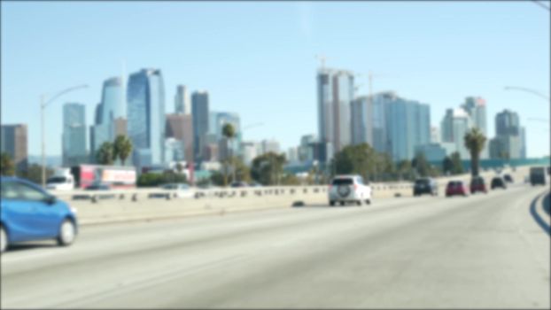 Driving on downtown streets of Los Angeles, California USA. Defocused view from car thru glass windshield on driveway. Blurred road with vehicles in Hollywood. Camera inside auto, LA city aesthetic.